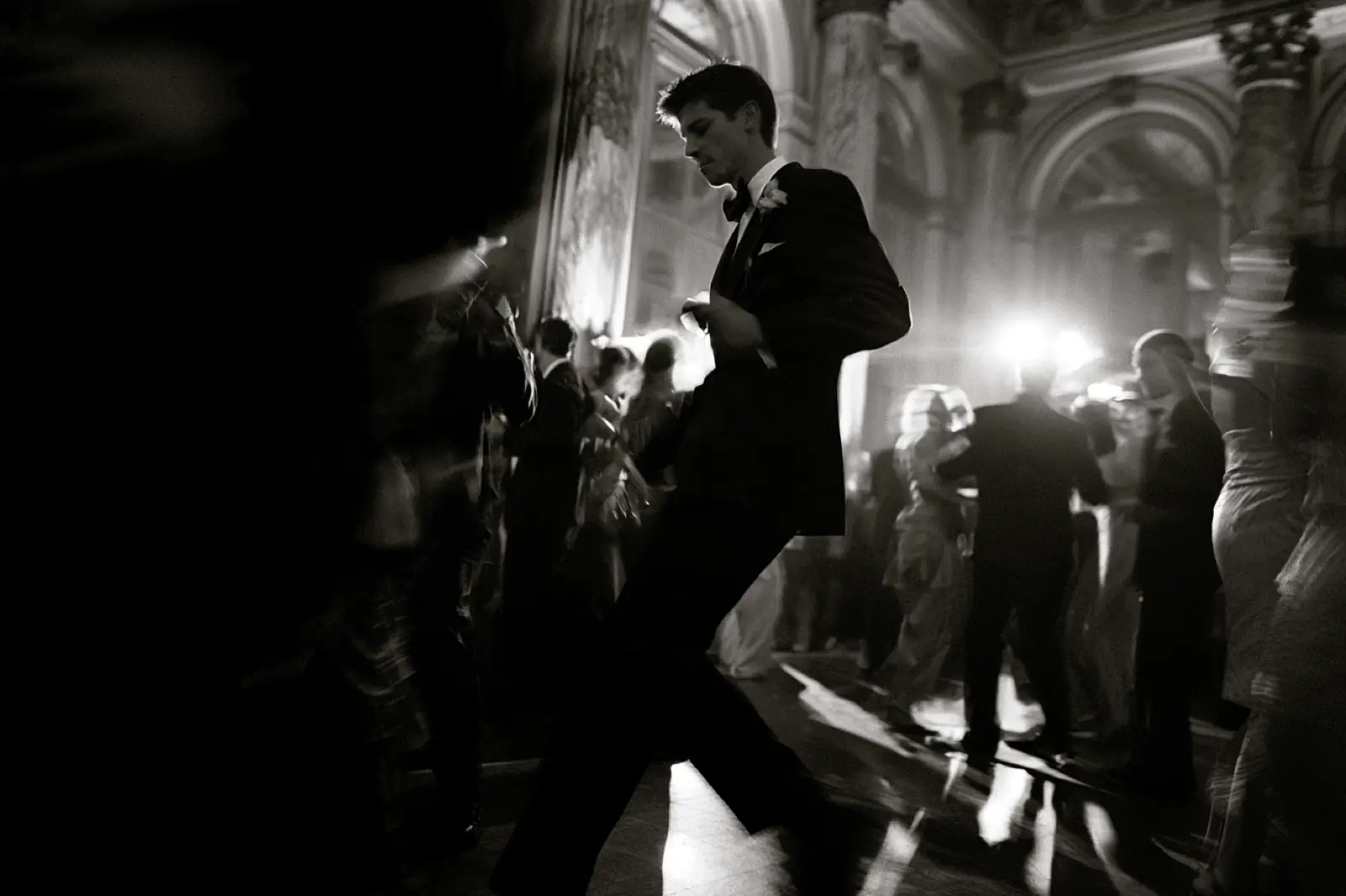 A groom crossing the dance floor, in black and white