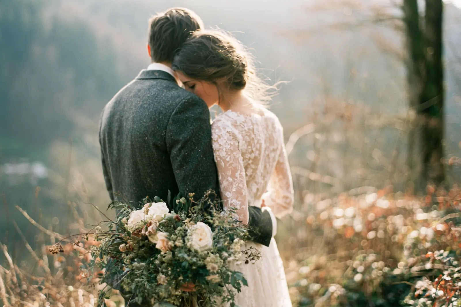 A groom holding a bride close in soft evening light among flowers