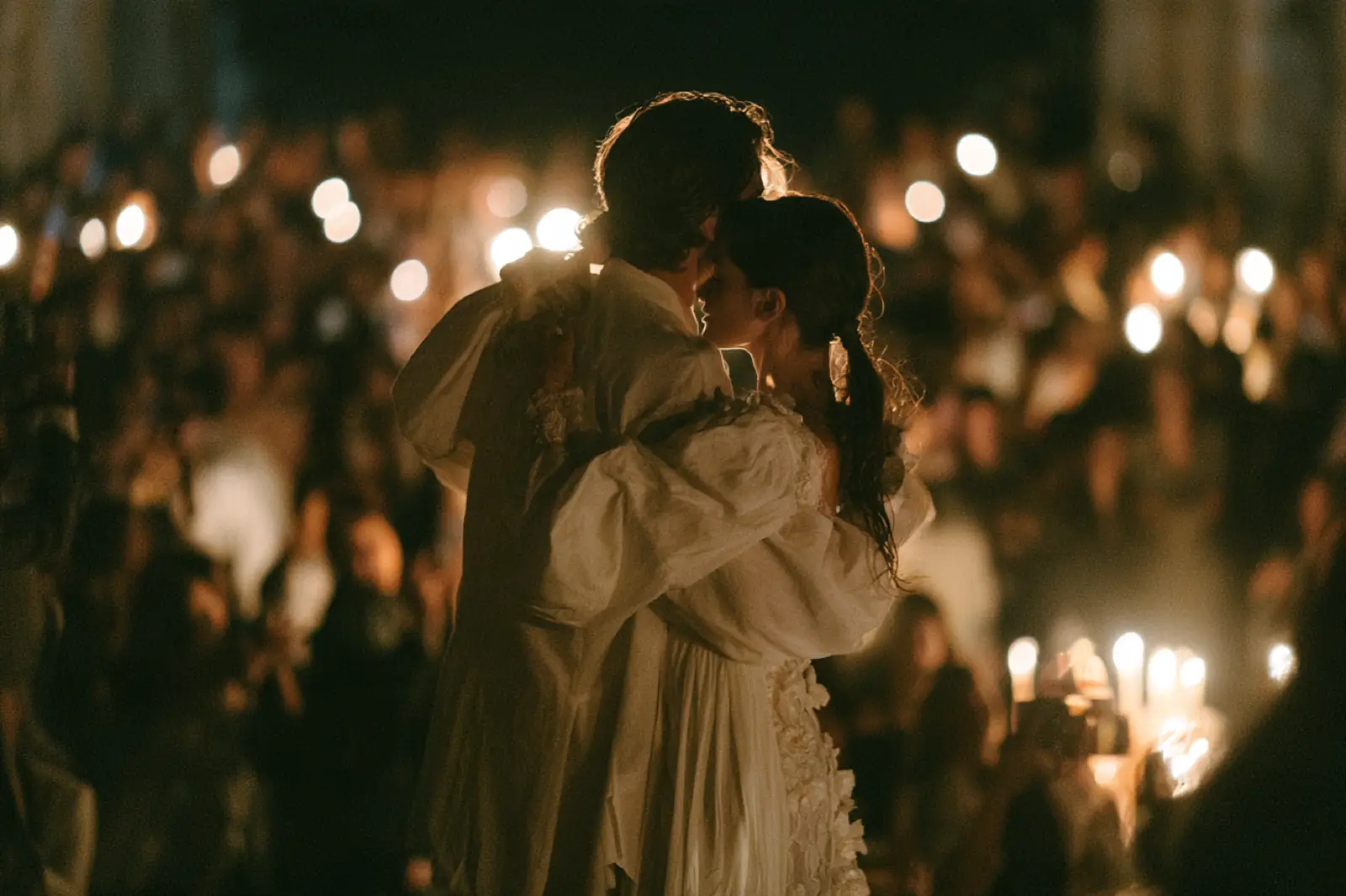 A newly married couple kissing among warm reception lights