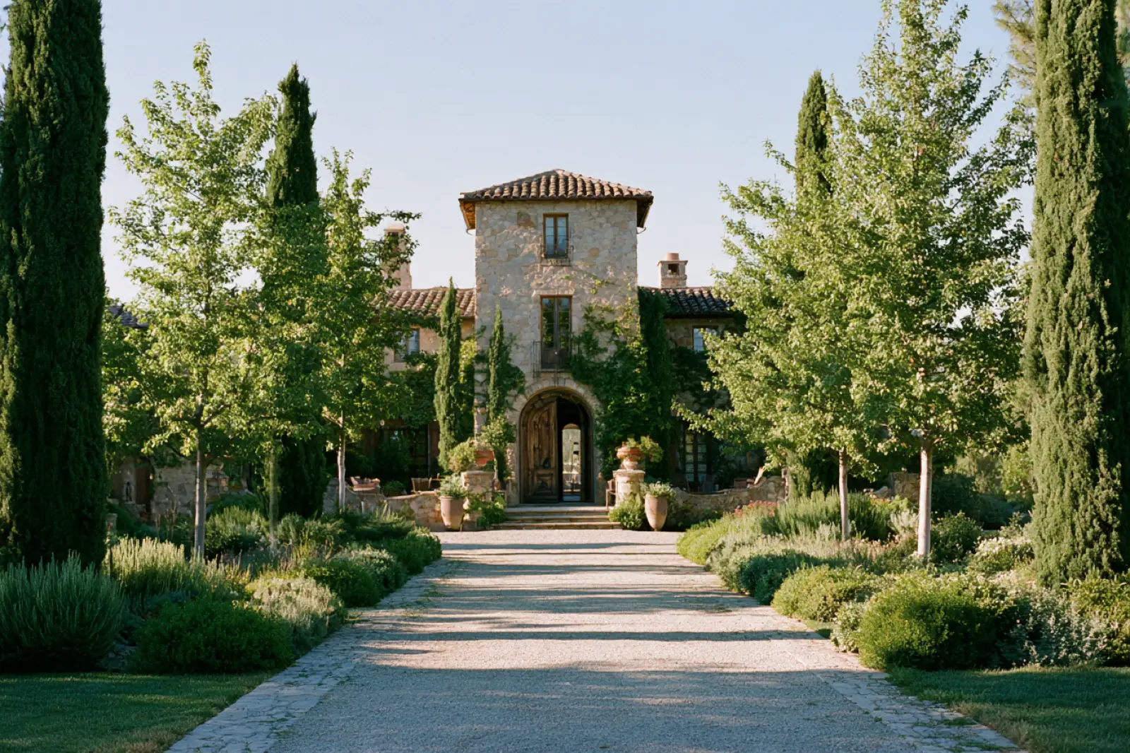 A villa gate at the end of a path between cypresses