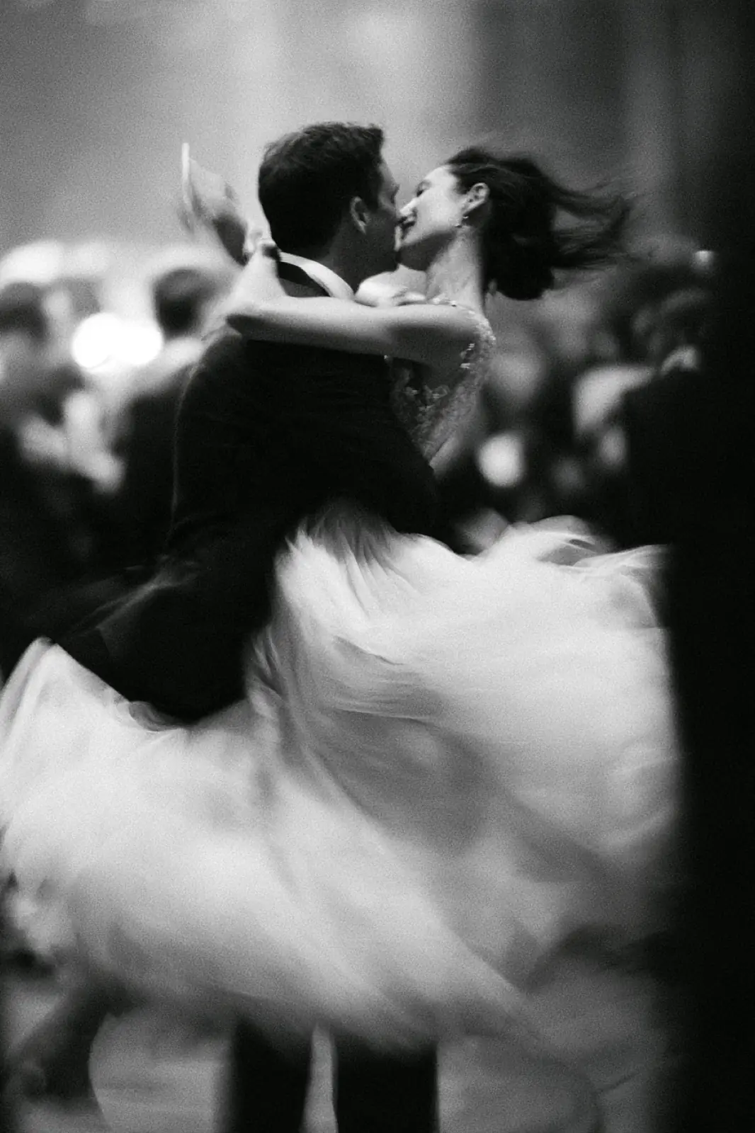 A couple dancing, her dress a blur, in black and white