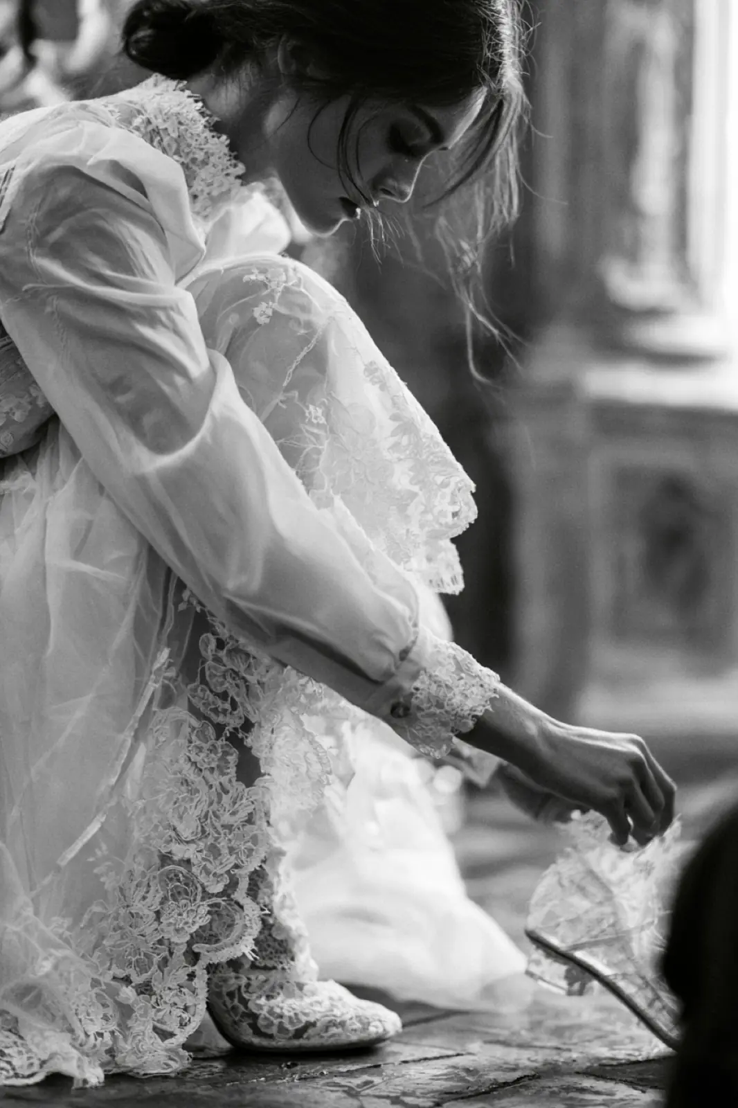 A bride in lace lifting her skirt on a flight of stone steps
