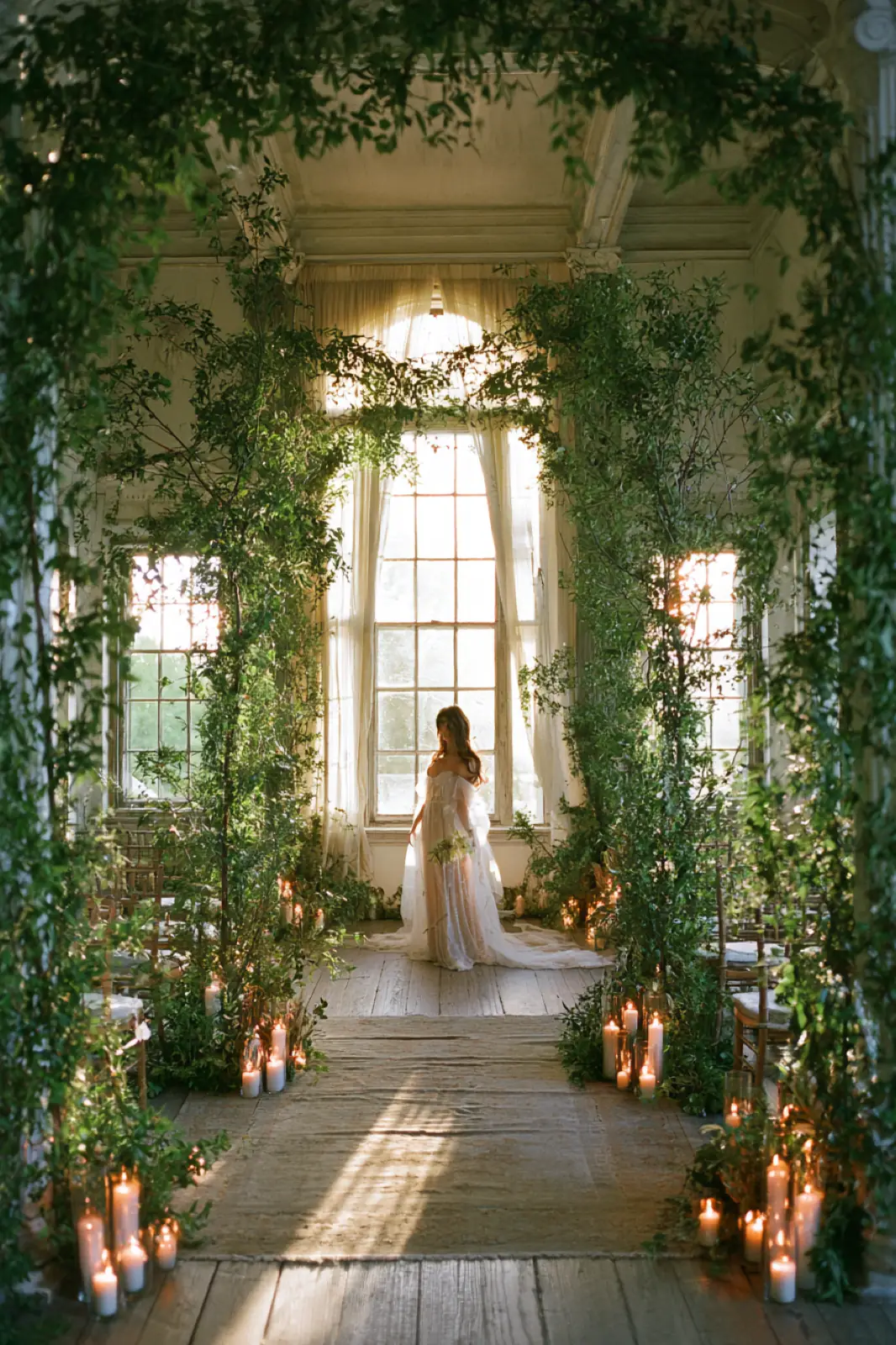 A bride standing in a glasshouse doorway framed by climbing green leaves