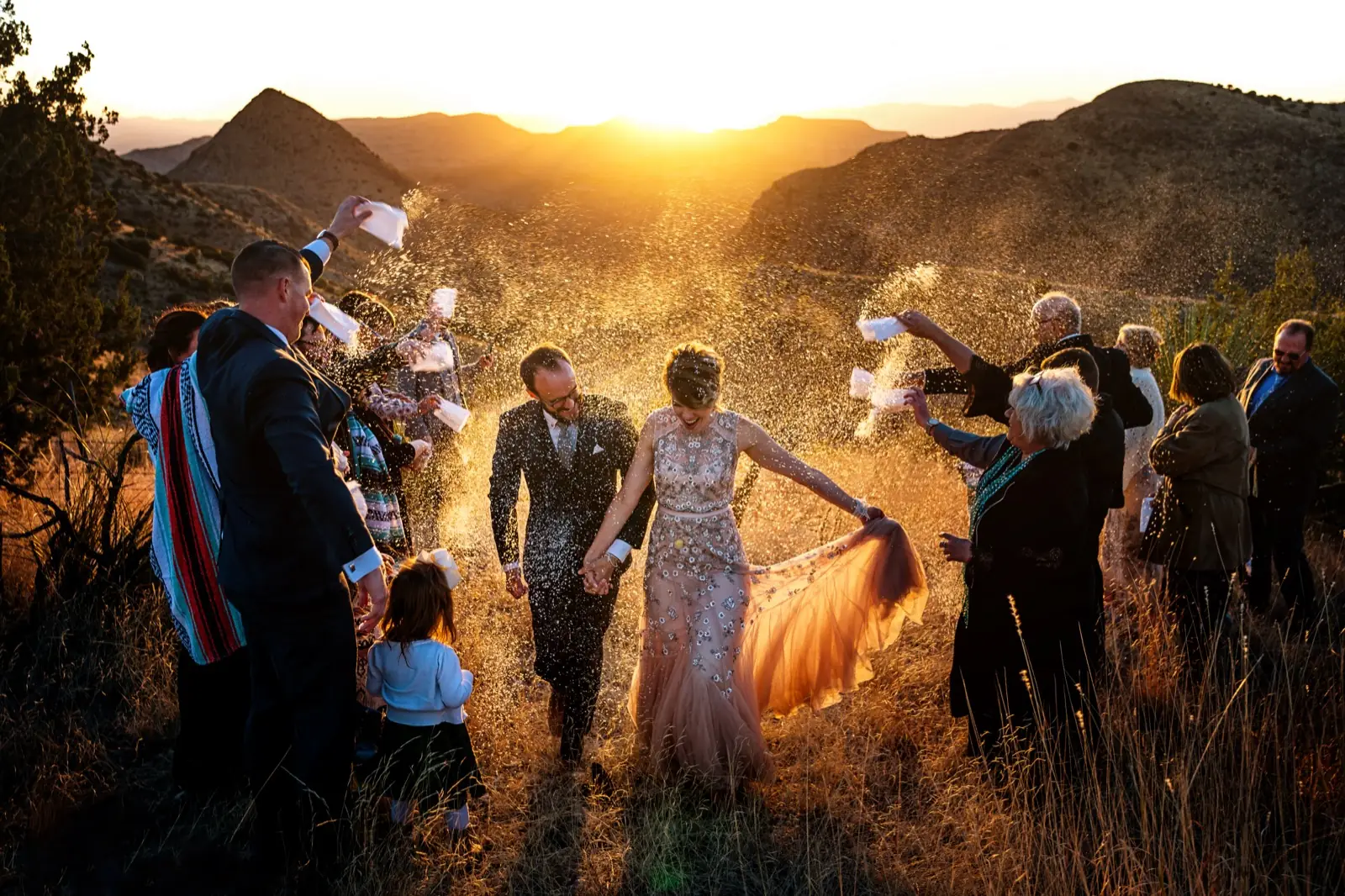 A couple walking through a field at sunset