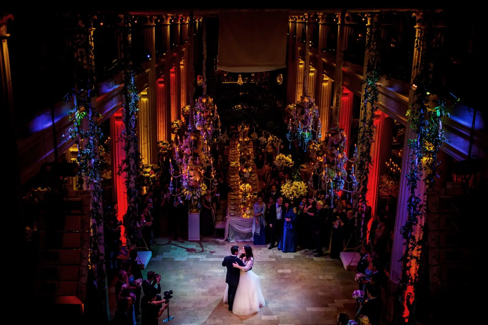 A couple alone on the floor of a vast candlelit hall
