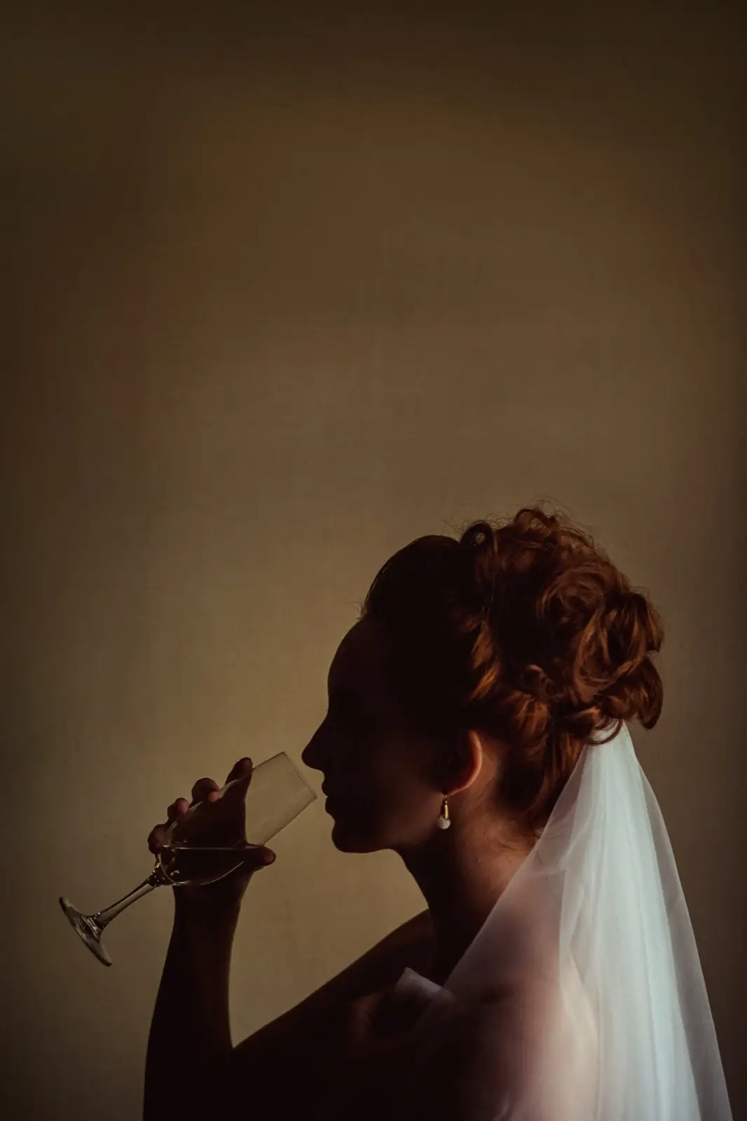 A bride in profile, a glass raised to the window