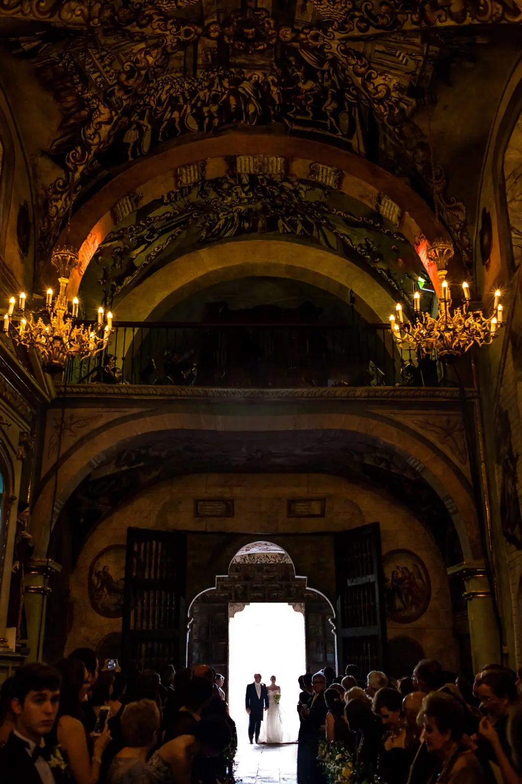 A painted chapel lit by chandeliers, a couple small at the far end