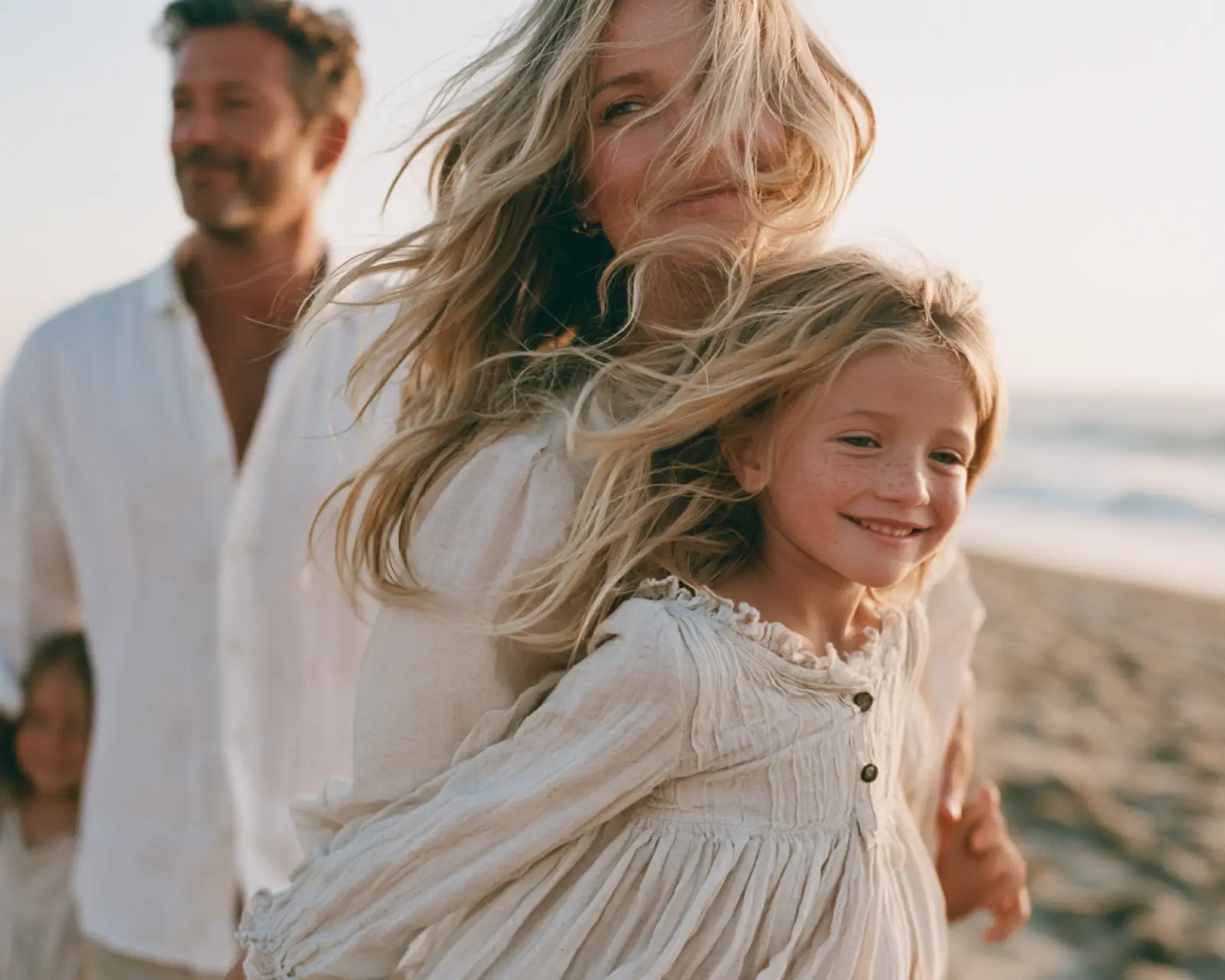 A family on the beach in wind and low sun