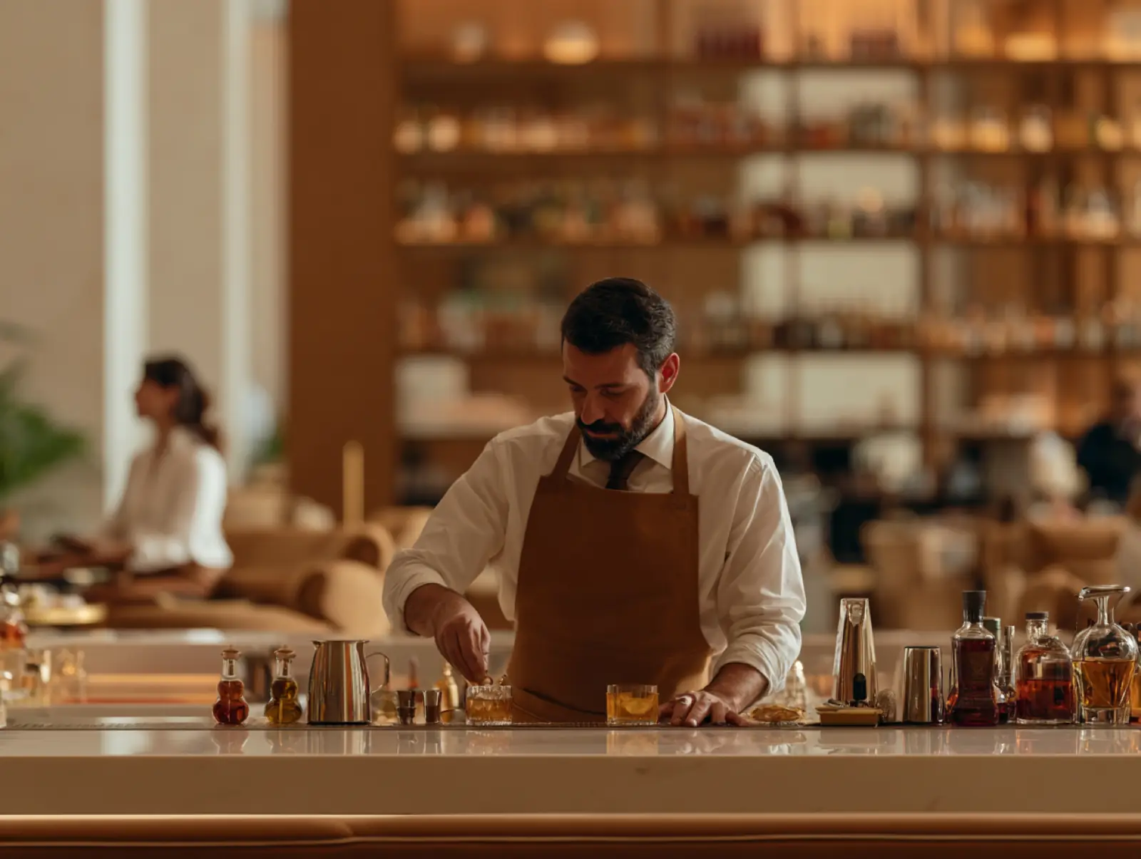 A chef in a leather apron working at a long marble counter