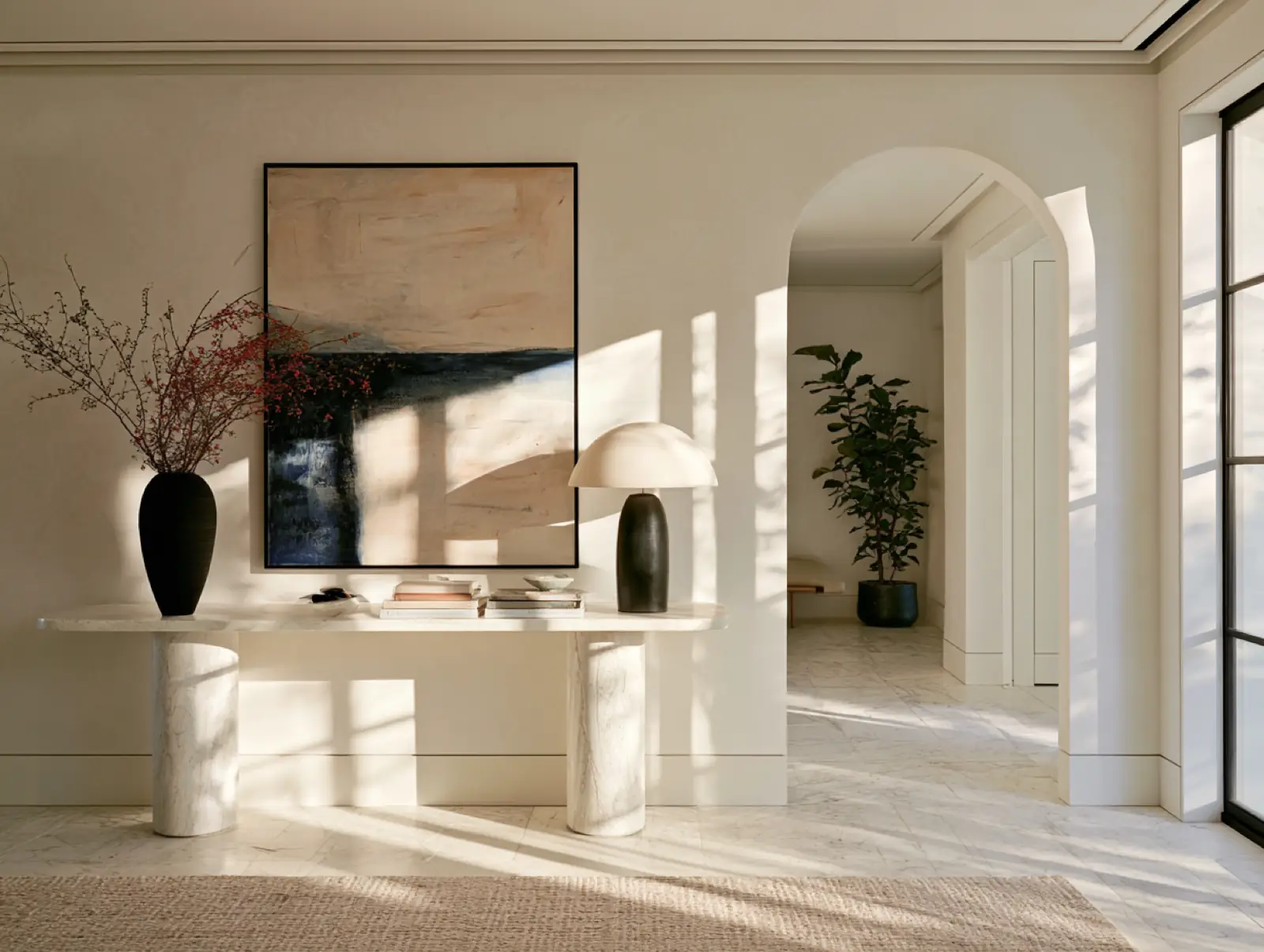 A white hall with a long table, arched openings and a picture on the wall