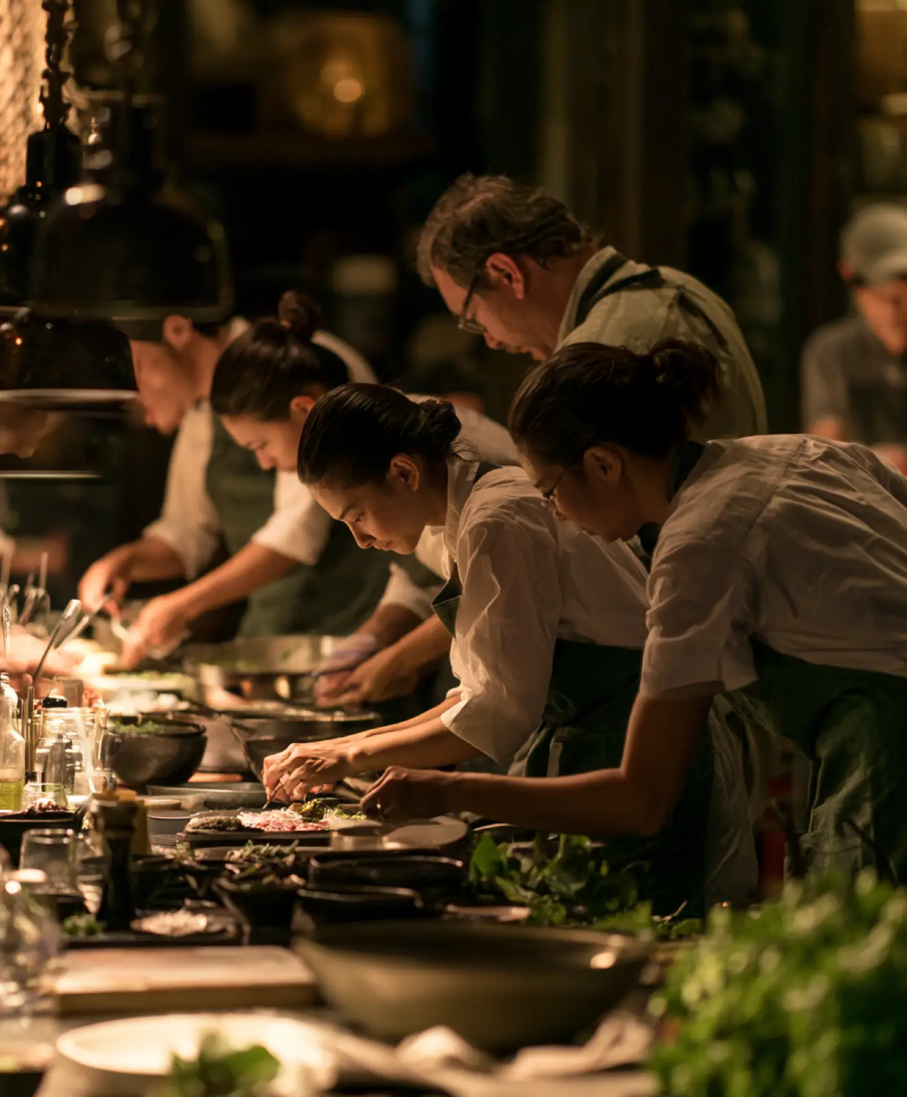 A kitchen crew plating dishes together at the pass